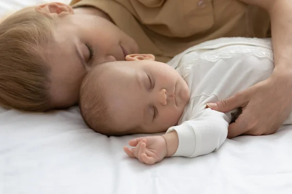 Peaceful tired mother and calm infant sleeping together