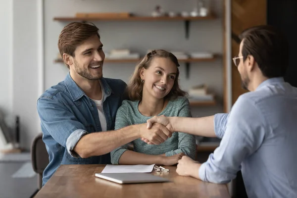 Gelukkig paar kopers handdruk relator op kantoor vergadering — Stockfoto