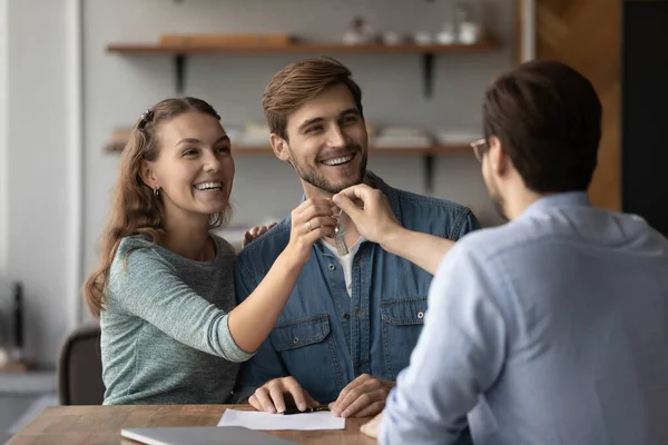 Relator masculino dar las llaves a los compradores de pareja emocionados — Foto de Stock