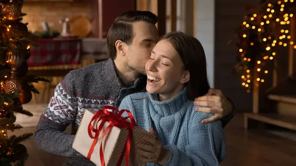 Affectionate loving young husband giving Christmas gift to wife. — Stock Photo, Image