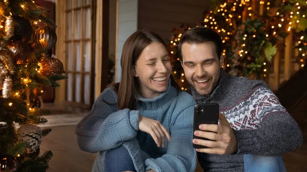 Sorrindo positivo jovem europeu casal de ligação olhando para a tela do smartphone. — Fotografia de Stock