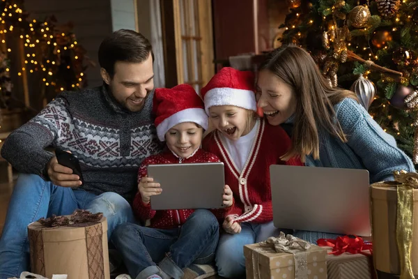 Jovens pais felizes assistindo desenhos animados engraçados de Natal com crianças. — Fotografia de Stock