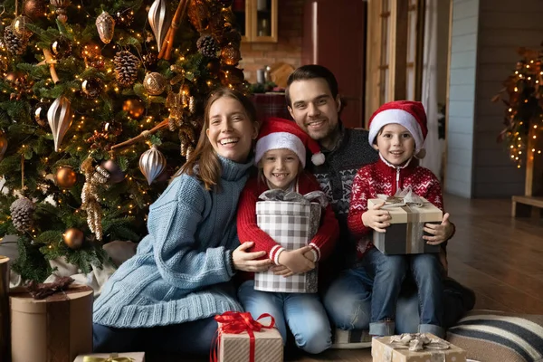 Retrato de família feliz emocional sentado perto da árvore de Natal decorada. — Fotografia de Stock