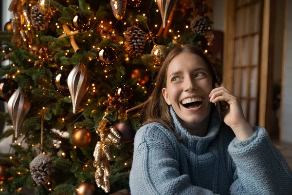 Młoda szczęśliwa Europejka trzyma telefon komórkowy gratuluje Bożego Narodzenia. — Zdjęcie stockowe