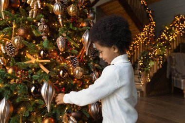 Küçük Afrikalı Amerikalı çocuk Noel 'de köknar ağacı süsler