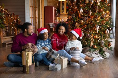 Çocuklu mutlu etnik aile Noel hediyeleri yazıyor.