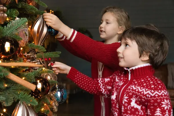 Glücklich aufgeregte kleine Kinder schmücken Weihnachtsbaum mit Kugeln. — Stockfoto