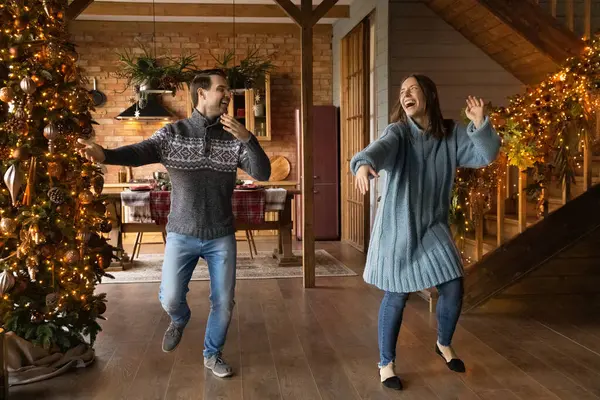 Überglückliches verrücktes junges Ehepaar tanzt neben Weihnachtsbaum. — Stockfoto