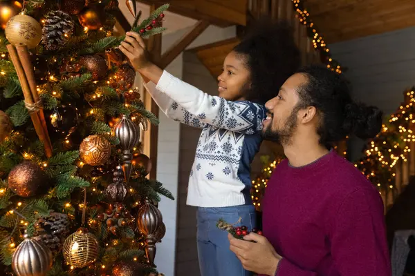 Kleines Mädchen hilft Papa, Tanne zu Weihnachten zu schmücken — Stockfoto