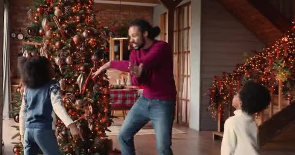 Heureux père afro-américain dansant avec des enfants près de l'arbre de Noël. — Video