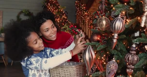 แฮปปี้ สาวแอฟริกันอเมริกันตัวเล็กตกแต่งต้นคริสต์มาสกับแม่ . — วีดีโอสต็อก