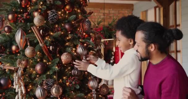 Vidám afro-amerikai gyerek játszik apával közel karácsonyfa. — Stock videók