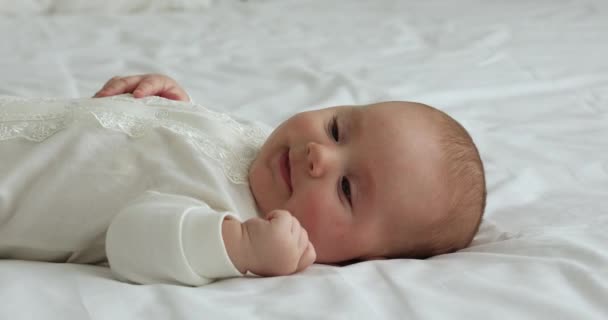 Charmante mooie baby liggend op bed op zoek naar afstand — Stockvideo