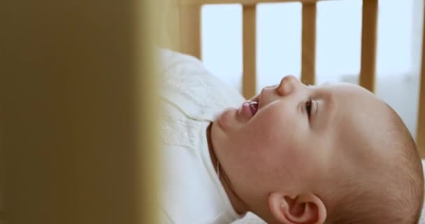 Крупним планом любляча мати цілує свою новонароджену дитину, що лежить в ліжечку — стокове відео