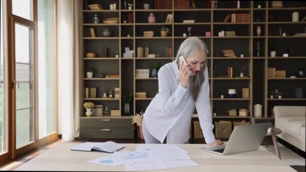 Χαμογελώντας μεγαλύτερης ηλικίας επιτυχημένη επιχειρηματίας χρησιμοποιώντας κινητό τηλέφωνο κάνουν κλήσεις που σχετίζονται με την εργασία — Αρχείο Βίντεο