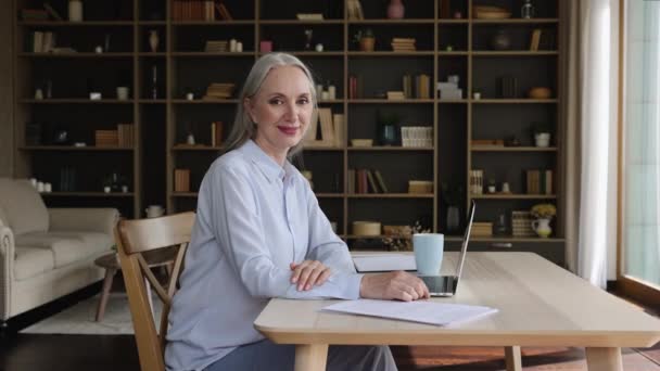 Μεγαλύτερη γυναίκα επιχειρηματίας κάθεται στο γραφείο χαμόγελο ματιά στην κάμερα — Αρχείο Βίντεο