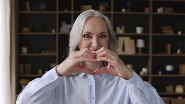 Headshot ritratto donna anziana mostrano la forma del cuore con le dita — Video Stock