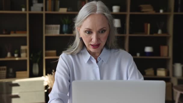 Mujer mayor sentarse en el escritorio lee noticias en línea se siente emocionado — Vídeos de Stock