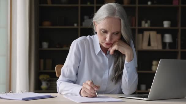 Focalisé 50 femme d'affaires à la recherche à travers les documents papier et utiliser un ordinateur portable — Video