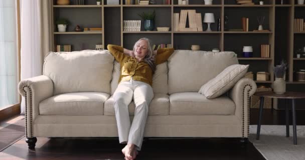 Spokojny starsza kobieta umieścić ręce za głową relaks na kanapie — Wideo stockowe