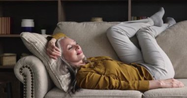 Yaşlı kadın kanepede uzanıyor, keyfine bakıyor, temiz havanın tadını çıkarıyor.