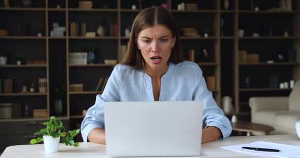 Возмущенная молодая женщина сердится иметь дело с проблемой на ноутбуке — стоковое видео