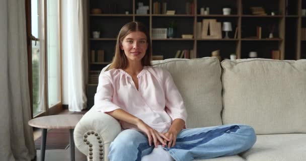 Kalm glimlachende jonge dame huiseigenaar poseren voor portret op de bank — Stockvideo