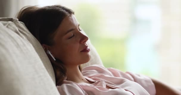 Szczęśliwa milenijna kobieta relaksująca się w słuchawkach słuchając audiobooka — Wideo stockowe