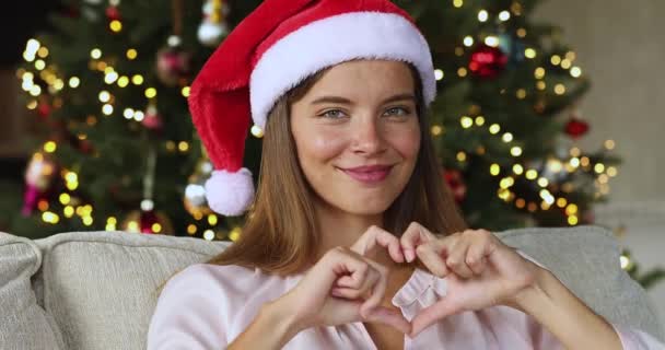 Female teenager in Santa hat making love symbol of fingers — Stock Video