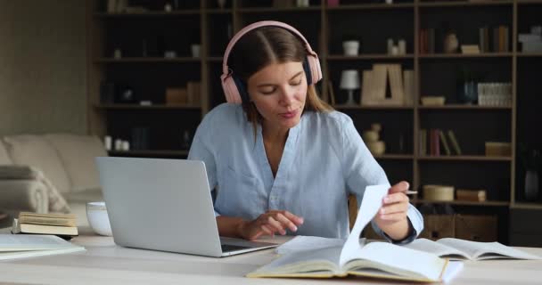 遠くの学習に従事ヘッドフォンで若い女性のリモート学生 — ストック動画