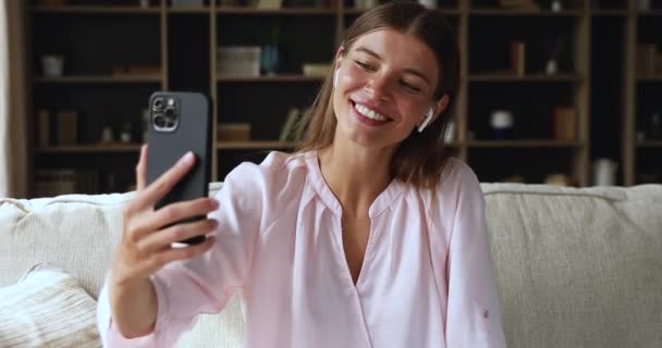 Mujer joven feliz en auriculares grabar mensaje de vídeo en el teléfono inteligente — Vídeos de Stock