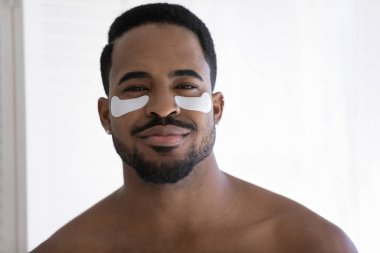 Portrait of African shirtless man with applied under-eye patches clipart