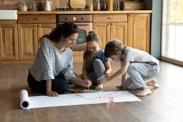 Glückliche Mutter zeichnet mit kleinen Kindern zu Hause. — Stockfoto