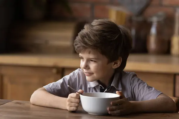 Drömmande leende liten pojke äter snabb frukost. — Stockfoto