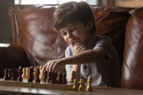 Interessierter kleiner entzückender Junge, der allein zu Hause Schach spielt. — Stockfoto