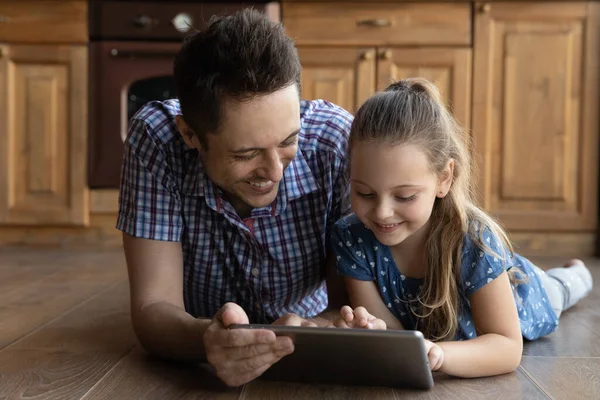 Cuidar do pai jovem usando tablet computador digital com a filha pequena. — Fotografia de Stock