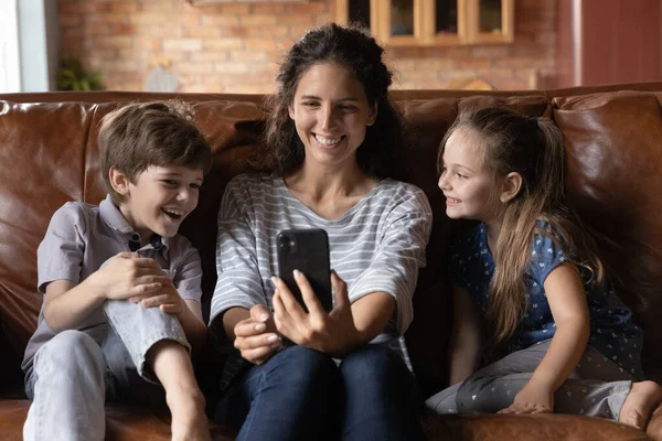 Happy young mother using cellphone with kids. — Stock Photo, Image
