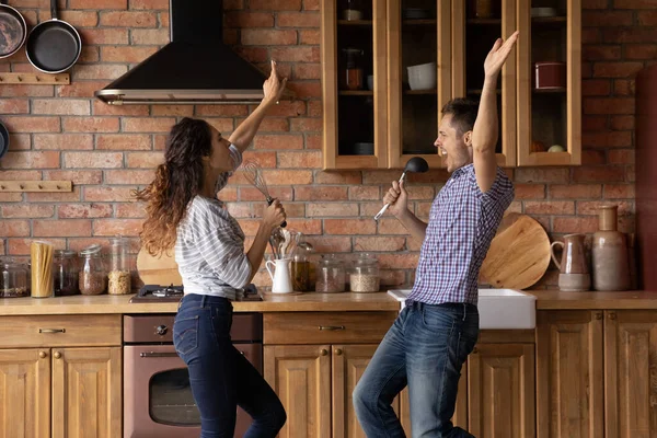Överlycklig ung uppriktig familj par som har kul i köket. — Stockfoto