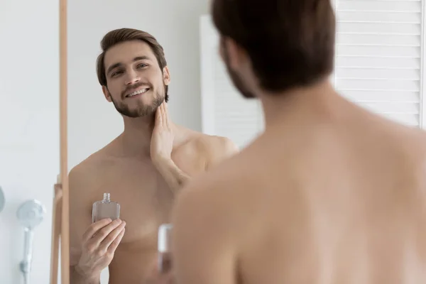 Young man applying to skin aftershave lotion — Stock Photo, Image