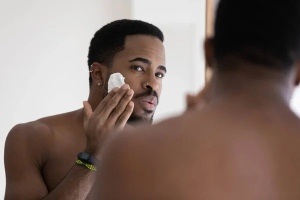 African man looking in mirror applying shaving foam on face — Stock Photo, Image