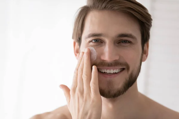 Close up portrait handsome man applying facial cream — Stock Photo, Image