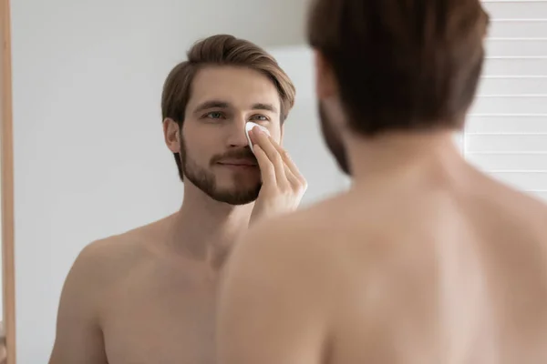 Hombre sosteniendo almohadilla de algodón cara de limpieza con tónica —  Fotos de Stock