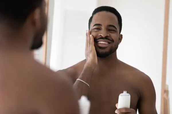 Afrikansk man bryr sig om ansiktshud tillämpa lotion njuta av processen — Stockfoto