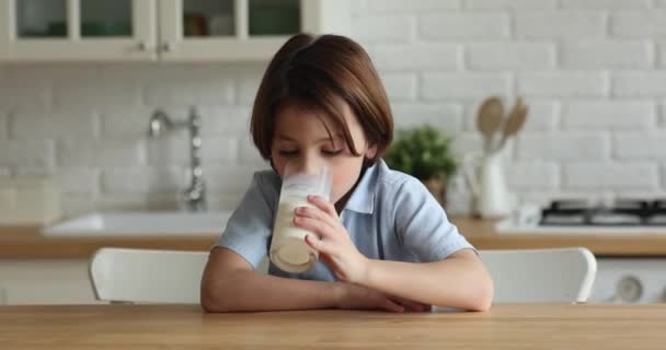 Adorable niño sediento bebiendo vaso de leche. — Vídeo de stock