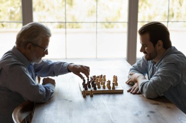 Olgun babası olan genç bir adam birlikte satranç oynuyor.