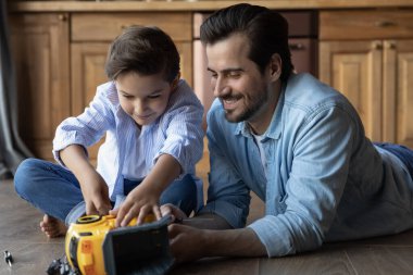 Mutlu babayı yakın, küçük oğlu oyuncak arabayı tamir ediyor.