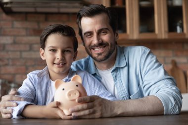 Domuz kumbarasıyla gülümseyen baba oğul portresi.