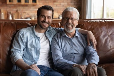 Aile portresi gülümseyen olgun baba ve yetişkin oğul kucaklaşması.