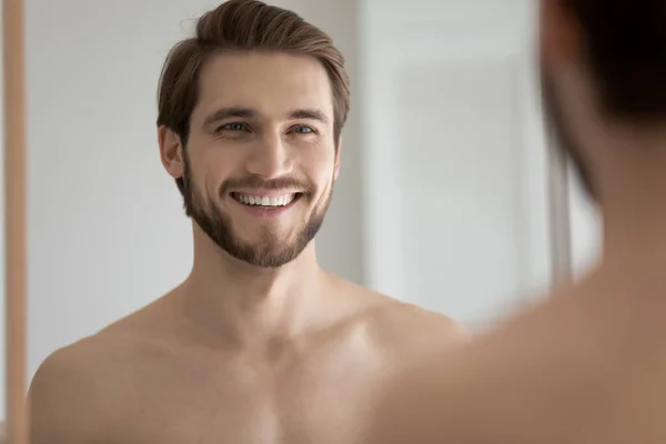 Portrait of young handsome shirtless man smile looks in mirror — Stock Photo, Image
