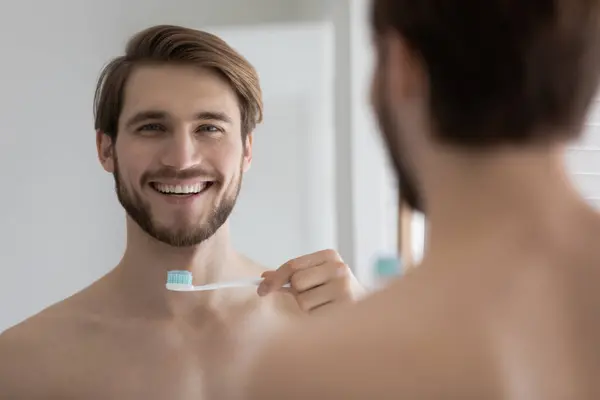 Handsome smiling shirtless man holding toothbrush with toothpaste — Stock Photo, Image